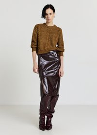 Pull en maille marron avec texture torsadée, jupe midi en cuir bordeaux élégante avec fente latérale, et bottes en cuir assorties au-dessus du genou.