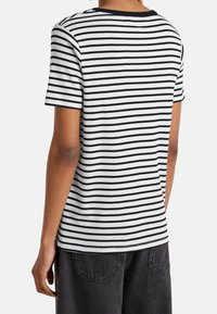 Randig T-shirt med svarta och vita horisontella ränder, rund hals, mjukt material, korta ärmar och avslappnad passform.