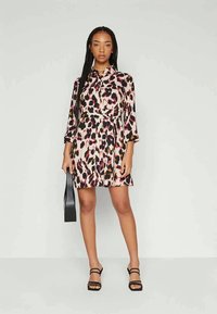 Satin obleka z leopardjim vzorcem v odtenkih roza, črne in bež. Ima ovratnik, dolge rokave in poudarjen pas.