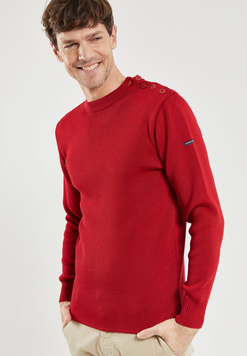 Roter gestrickter Pullover mit langen Ärmeln, gerippten Bündchen und einer vierknöpfigen Verzierung an der Schulter. Glatte Textur und taillierte Passform.