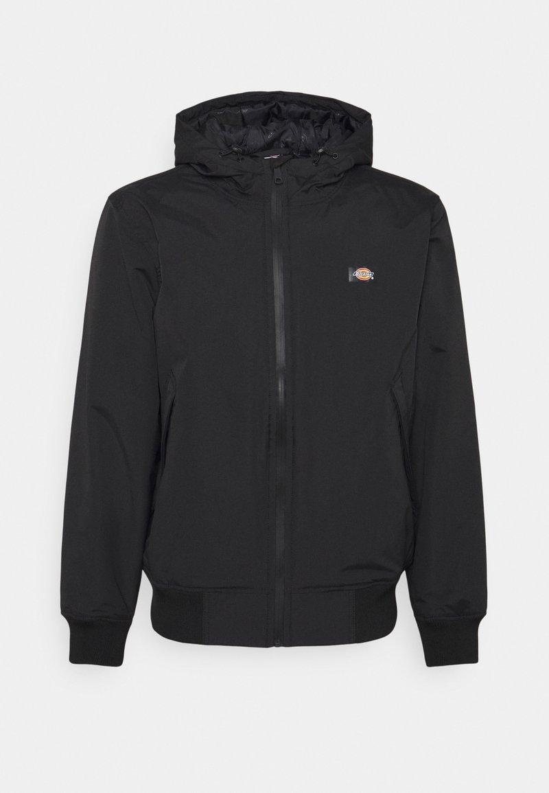 Veste noire zippée avec capuche, poignets élastiques, deux poches latérales et un petit logo coloré sur la poitrine gauche.