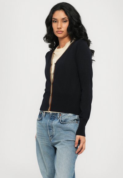 Cardigan navy con scollo a V, caratterizzato da un bordo multicolore e chiusura con bottoni. Realizzato in un materiale morbido con maniche lunghe e orlo a coste.