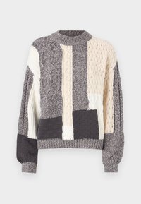 Pull en maille avec un design en patchwork présentant des couleurs grises, crème et des motifs texturés. Encolure et poignets côtelés, coupe oversize.