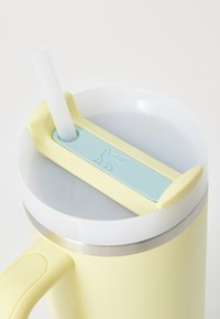 Gul isolert tumbler med en lys blå lokk og sugerør, med en rustfritt stål kant og et teksturert silikon grep med preget design.