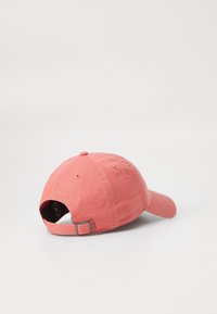 Gorra de béisbol de algodón rosa con visera curva, correa trasera ajustable y botón redondo en la parte superior. Presenta ojales de ventilación para mayor transpirabilidad.