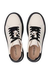 Baskets en cuir blanc avec lacets noirs, bout rond et semelle noire. Présente un broche décorative en strass sur les lacets.