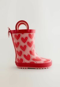 Pinkfarbener Gummiregenstiefel mit roten Herzmustern, rundem Zehenbereich und profilierter Sohle. Verfügt über rote Griffe oben für einfaches Anziehen.