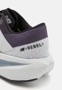Running shoe with a black mesh upper, textured white accents, a purple gradient heel, and a geometric white sole featuring "REBEL" branding.