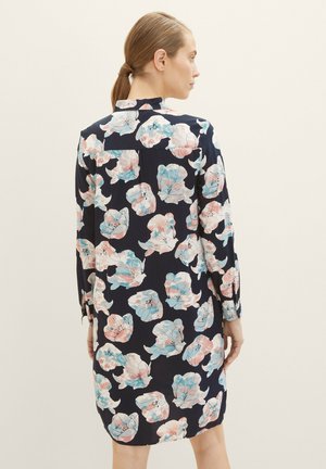 Bloemenjurk met lange mouwen, marineblauwe achtergrond en pastelkleurige bloemenpatronen in roze en blauw. Heeft een hoge halslijn en een relaxed fit.
