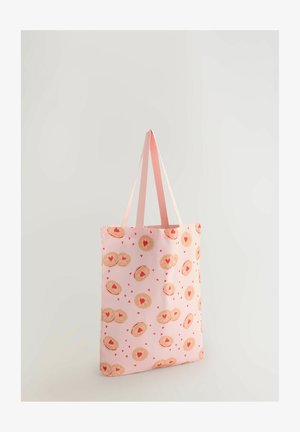 Rosa Tragetasche mit einem wiederholenden Muster aus herzförmigen Keksen und kleinen roten Herzen. Verfügt über zwei hellrosa Henkel und eine weiche Stofftextur.