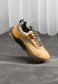 Zewnętrzne sneakersy z brązowym wierzchem wykonanym z siateczki i zamszu, kontrastującymi szarymi akcentami, gumową podeszwą i teksturowanymi sznurowadłami.