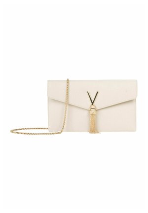 Pochette en cuir beige avec fermoir doré en forme de V, pompon doré et fine chaîne assortie pour porter à l'épaule, sur fond blanc.