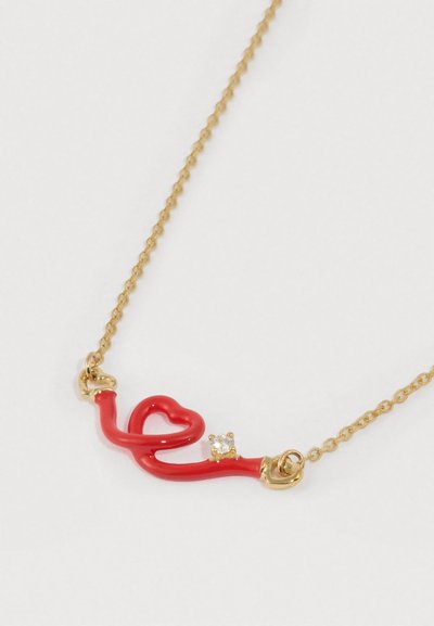 Κολιέ με κόκκινο σμάλτο σε κυματιστό σχέδιο καρδιάς, διακοσμημένο με ένα διαυγές strass, προσαρτημένο σε αλυσίδα με χρυσαφένια απόχρωση.