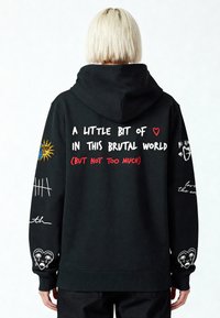 Čierna mikina s kapucňou na šnúrku. Na zadnej strane farebné grafiky a text, vrátane slnečného motívu a ilustrácií na rukávoch.