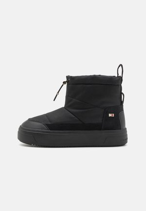 Botte d'hiver isolée noire avec semelle épaisse, cordon ajustable en haut, languette au talon et petit logo de la marque sur le côté.