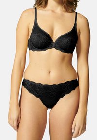 Ensemble de lingerie noire comprenant un soutien-gorge avec des bonnets lisses bordés de dentelle et une culotte assortie accentuée de dentelle avec des bords festonnés.