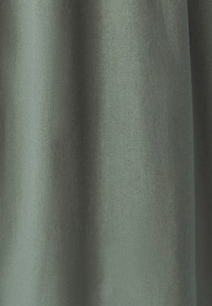 Teksturovana tkanina v utišani zeleni barvi, ki ima mehak, mat videz in padajoče gube, ki ustvarjajo vizualno globino in gibanje.
