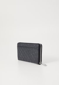 Černá kožená peněženka s embosovaným vzorem, s uzávěrem na zip a stříbrnými doplňky. Ploché obdélníkové tvary, hladká textura, minimalistický design.