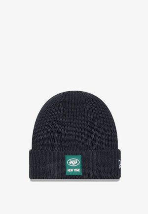 Bonnet en tricot bleu marine avec une texture côtelée, un revers plié et un patch rectangulaire vert affichant "NEW YORK" en lettres blanches.