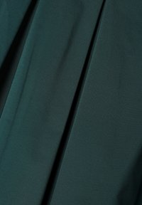 Teal stof met een gladde textuur, voorzien van diepe plooien. Het materiaal lijkt lichtgewicht te zijn, met subtiele variaties in kleur en glans.