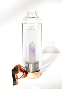 Bouteille d'eau en verre transparent contenant un point de cristal violet à l'intérieur, avec une base métallique et un accent en or rose, surmontée d'un couvercle sécurisé.