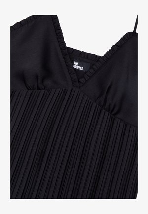 Robe plissée noire avec un décolleté en V et un tissu texturé. Des bretelles volantées ajoutent du détail. Étiquette "The Kooples" visible à l'intérieur.