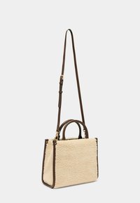 Sac en fausse fourrure beige avec des accents en cuir marron, deux poignées et une bandoulière amovible, de forme rectangulaire.