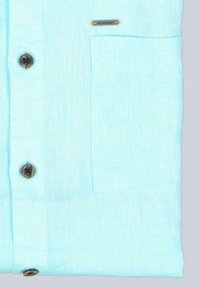 Hellblaues Kurzarmhemd aus strukturiertem Stoff; verfügt über eine Brusttasche und braune Kunststoffknöpfe. Kleines Logo auf der Tasche.