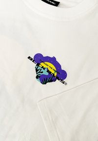 Witte katoenen t-shirt met een kleurrijke graphic op de borst, waarop een gestileerd berengezicht en tekst zijn afgebeeld. Korte mouwen, standaard pasvorm.