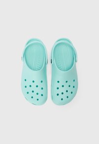 Light blue clogs made of plastic with vent holes, back strap, and textured insole. Smooth surface and rounded edges provide comfort.