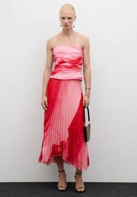 Strapless rode en roze geplooide jurk met een aansluitend lijfje en een vloeiende rok. Inclusief een kleine tas en sandalen met hoge hakken.