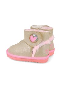 Botas de tobillo doradas con suelas de goma rosa, acentos de piel sintética y un detalle de corazón circular en el costado. Textura suave y diseño corto.