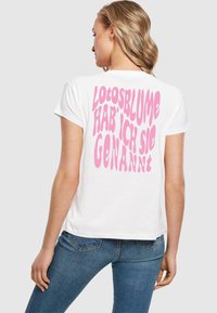 Weißes Baumwoll-T-Shirt mit großem pinken Text auf dem Rücken in einer verspielten Schriftart, der sagt: "Lotosblume hab' ich sie genannt."