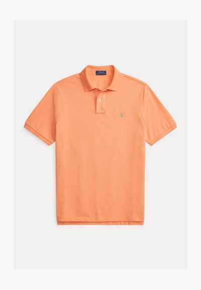 Polo orange en coton, doté d'un col classique, d'une patte à deux boutons et d'un petit logo vert brodé sur le côté gauche de la poitrine.