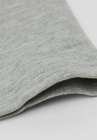 Szary teksturowany materiał z prążkowanym wzorem, złożonym brzegiem i miękkim wykończeniem, ukazujący lekką i casualową konstrukcję.