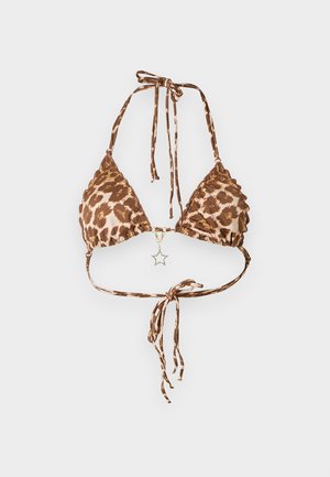 Γυναίκα που στέκεται φορώντας μπικίνι με λεοπάρ σχέδιο και μαύρα ψηλοτάκουνα σανδάλια σε απλό λευκό φόντο.