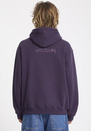 Felpa di cotone viola con cappuccio regolabile e polsini a costina. Presenta la parola "VOLCANO" in carattere gotico rosa sul retro.