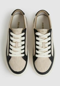 Beige canvas sneakers met zwarte leren accenten, ronde neus, witte veters en een gestructureerd oppervlak. Verstevigde hiel en minimalistisch ontwerp.