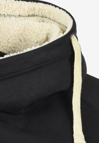 Sudadera negra con forro de felpa beige, que presenta una capucha con cordón y cuerdas de color crema en contraste. Tela exterior suave y detalles acanalados.