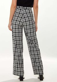 High-waisted plaid trousers in black and white, featuring a straight leg design and smooth texture with a subtle sheen.