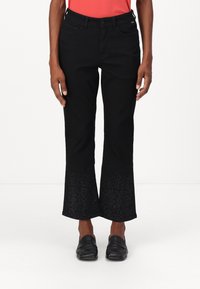 Schwarze Schlagjeans aus Denim mit einem strukturierten Blumenmuster am Saum. Der Bund verfügt über Gürtelschlaufen und Fronttaschen.