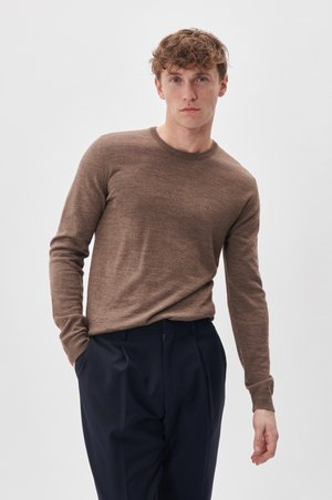 Suéter marrón de manga larga hecho de material suave, con un cuello redondo. Combinado con pantalones oscuros de corte navy, presentando un ajuste relajado.