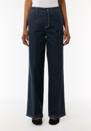 Weite Jeans aus Denim in dunklem Indigo mit Kontrastnähten, normaler Taille, vorderen Taschen und einer glatten Textur. Flache Vorderseite.