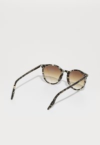 Gafas de sol carey con montura redondeada, lentes marrones degradados y varillas delgadas con acentos en dorado y crema.