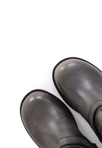 Botas de tobillo de cuero gris con una textura suave, puntera redonda y suela de goma negra. Presentan costuras a lo largo de los bordes y una correa ajustable.