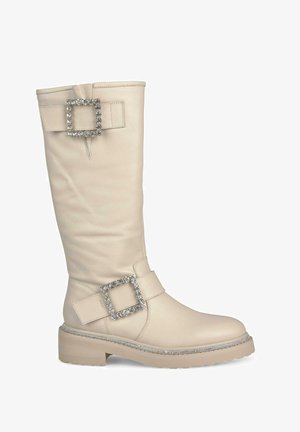Botas beige hasta la rodilla hechas de cuero suave, con dos grandes hebillas cuadradas adornadas con pedrería y una suela gruesa.