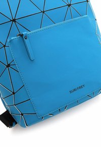 Mėlynas geometrinis kuprinės modelis su juodu trikampiu raštu, su priekinėmis kišenėmis, lygi tekstūra ir prekės ženklu "SURFREY" šone.