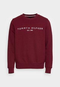 Bordowy sweter z nadrukiem "TOMMY HILFIGER EST. 1985". Wykonany z miękkiego materiału, z długimi rękawami oraz ribbowanymi mankietami i dołem.