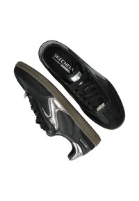 Zwarte sneakers met een textuur, metallic zilveren accenten, vetersluiting en een rubberen zool. Branding zichtbaar aan de zijkant.