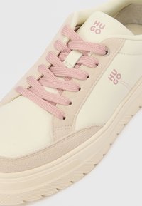 Cream and pink sneaker with suede and smooth leather materials, featuring pink laces and HUGO branding on the side. Textured outer sole.